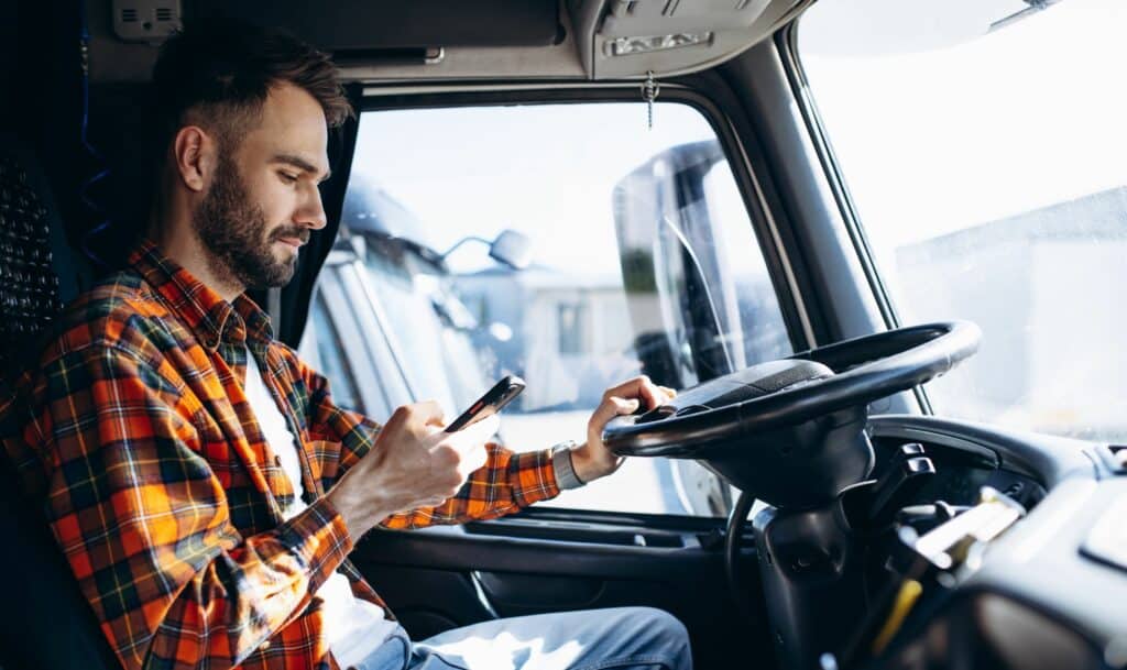 trucker in a cabin of his truck with iphone