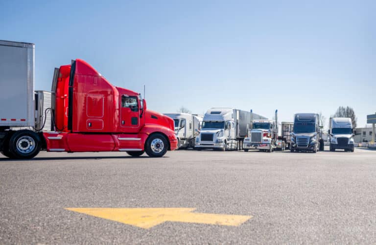 Lateral of red semi with trucks in background