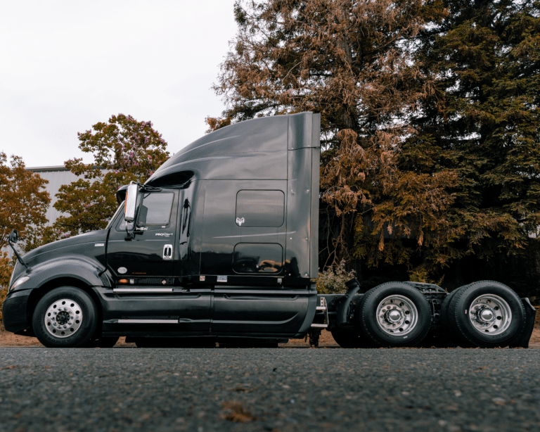 Black semi cab against trees