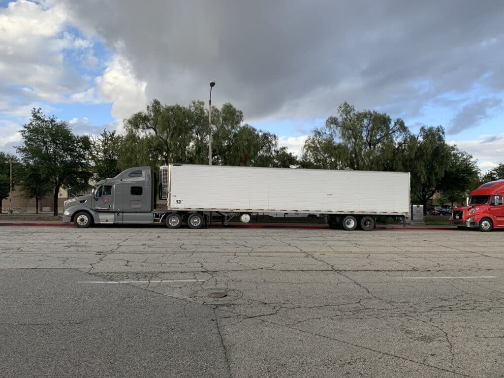side shot of big rig with grey cabin against trees