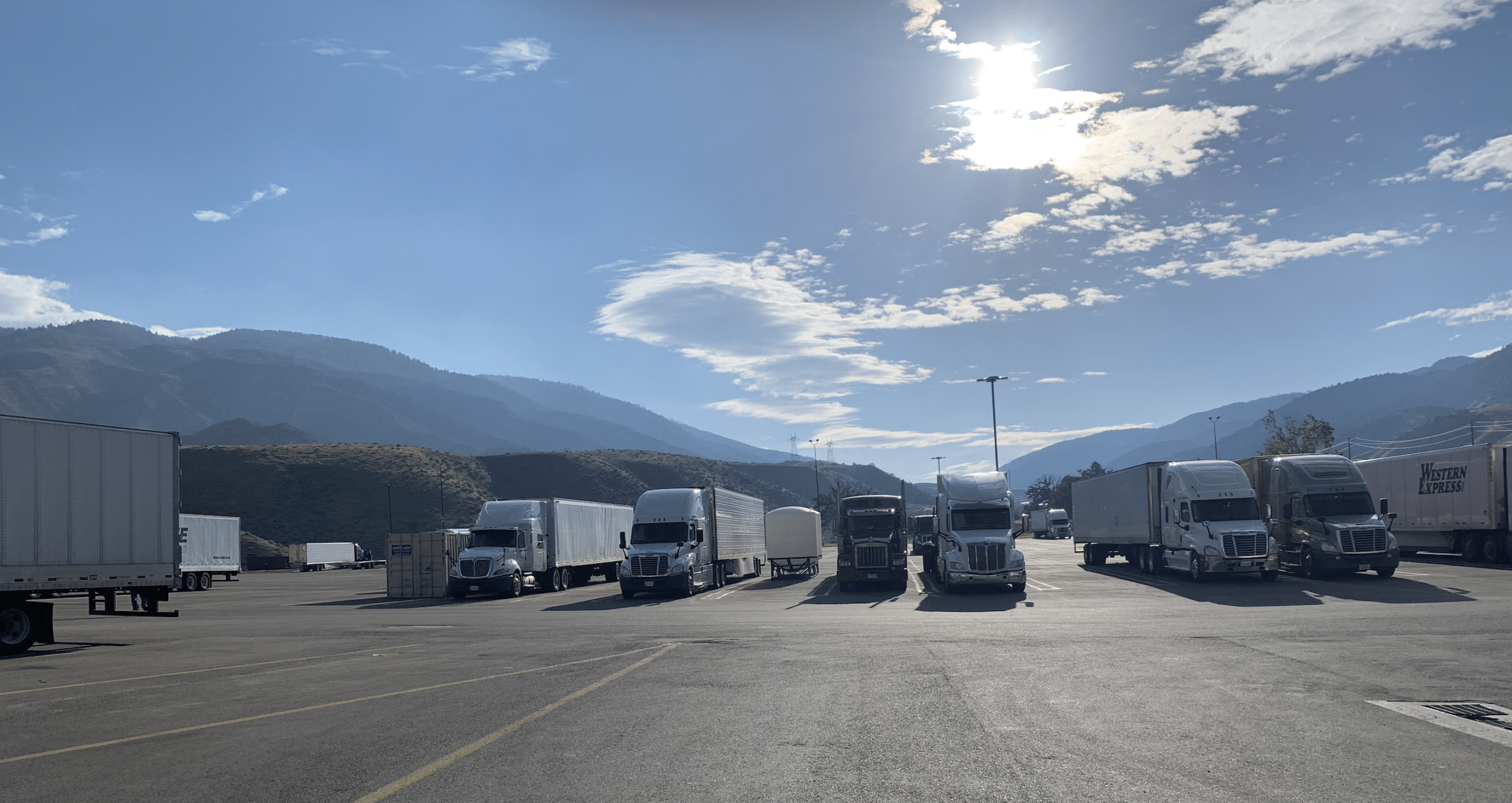 Big semis in parking lot under shining sun