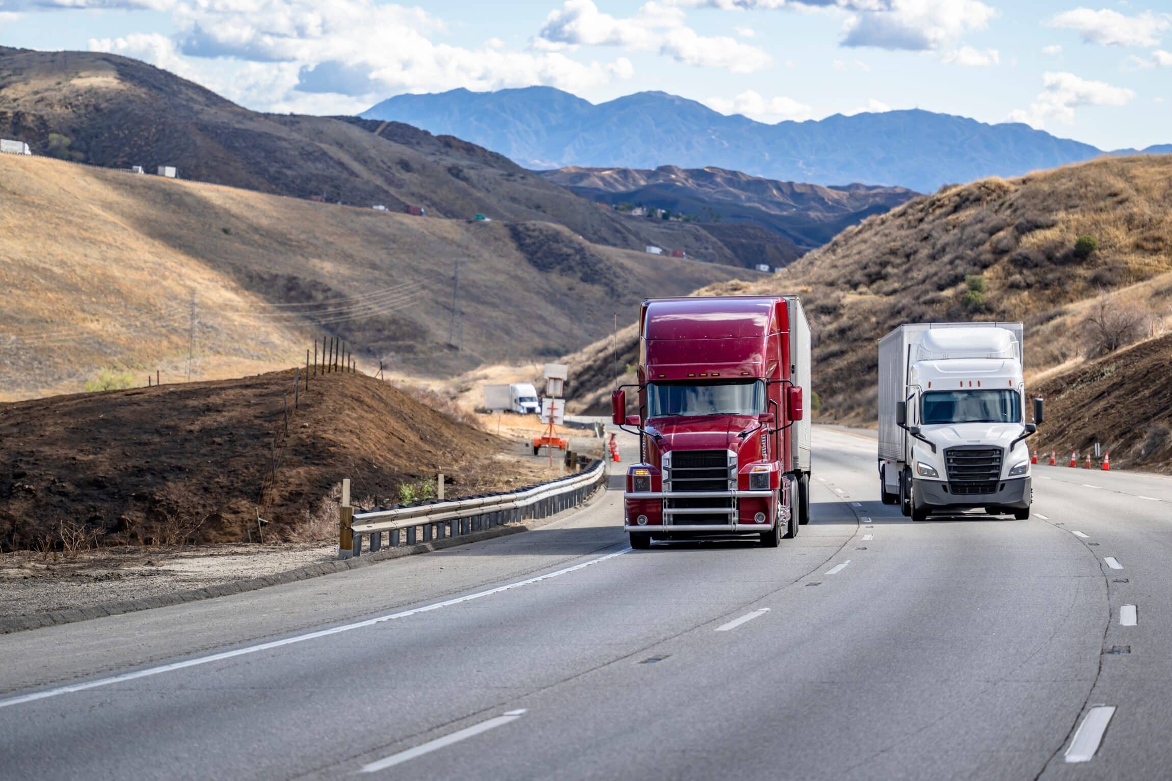 Convoy of a industrial transportation burgundy and white big rig semi trucks