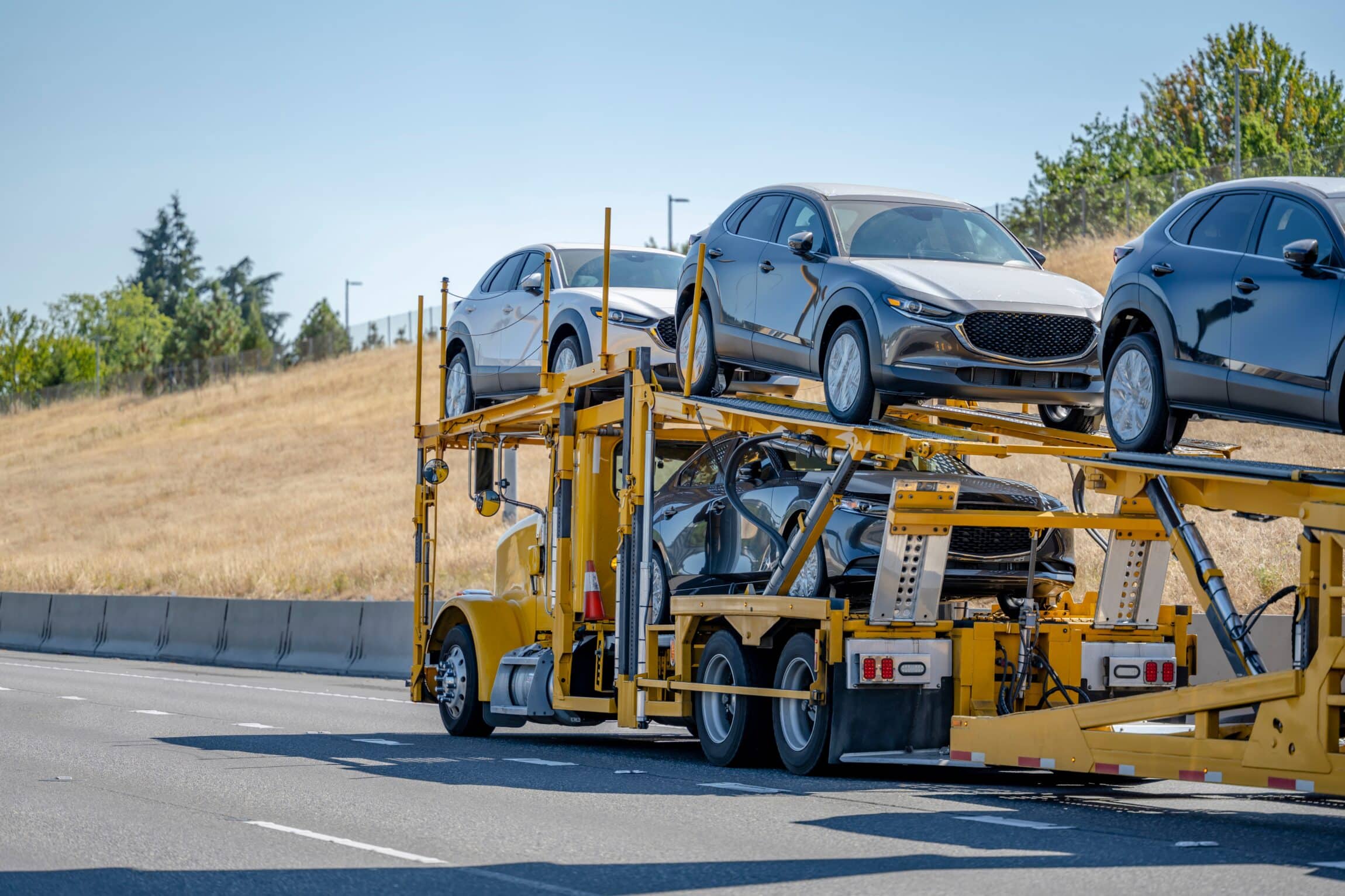 Commercial bright yellow big rig industrial car hauler semi truck transporting cars