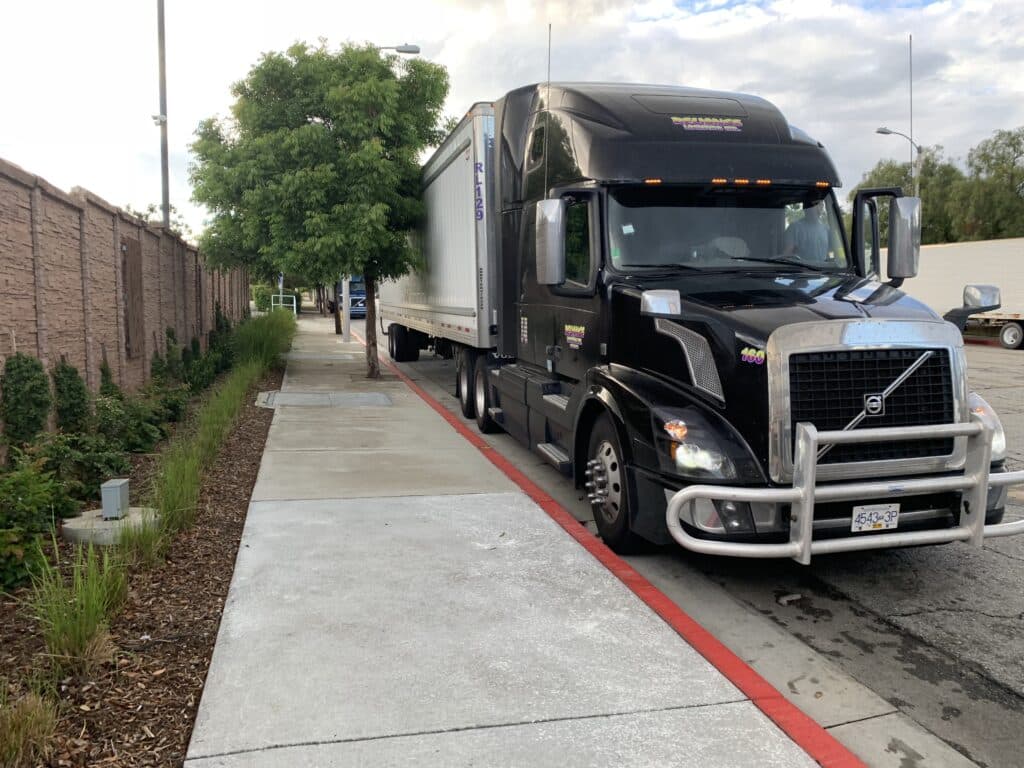 Black semi parked next to sidewalk
