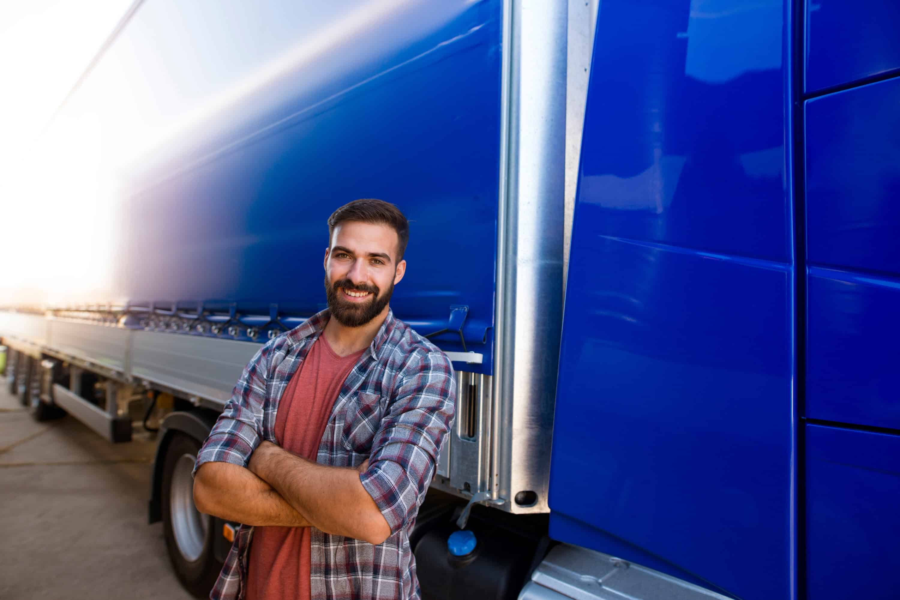 A trucker standing near a blue truck
