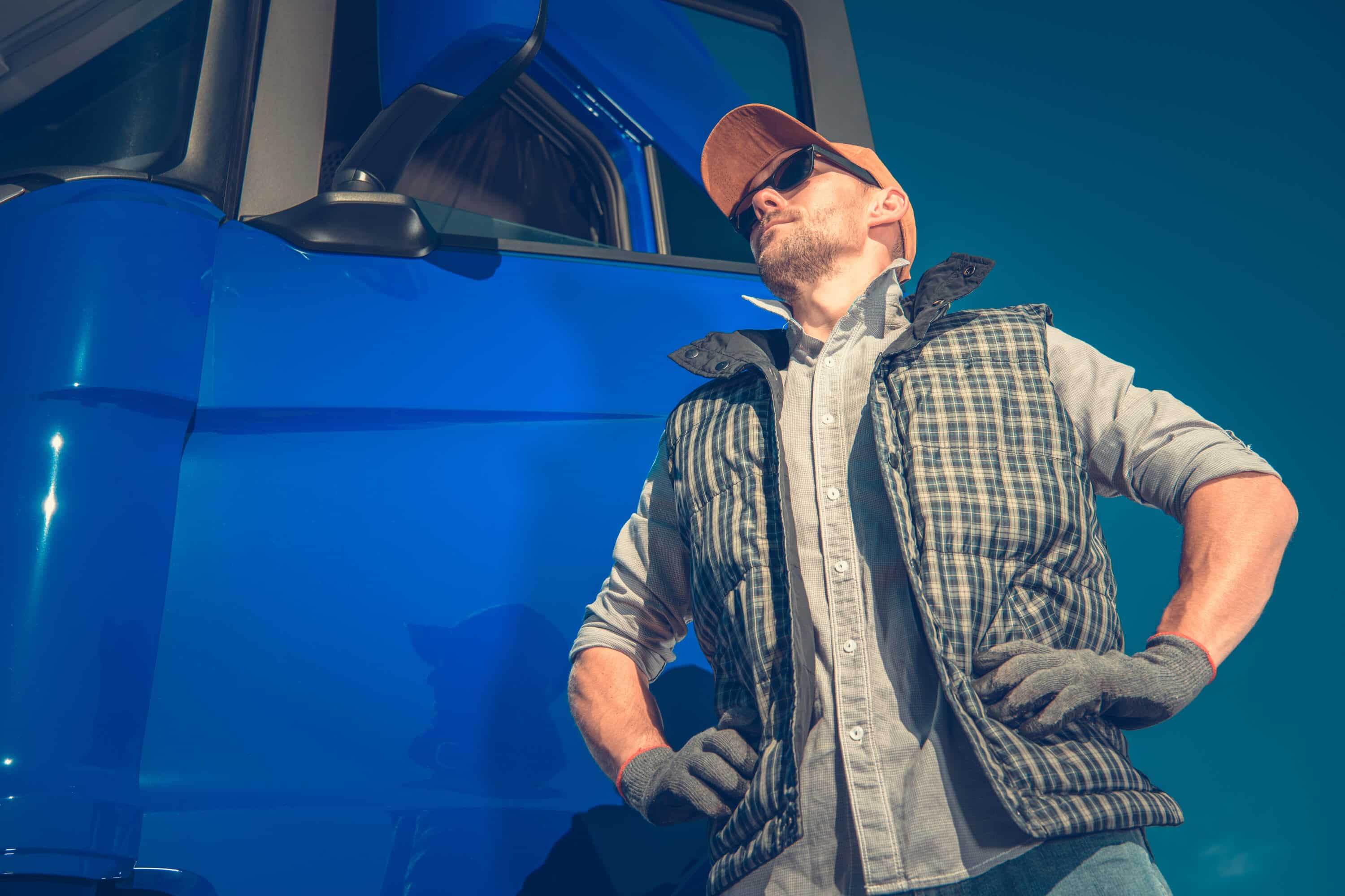 Truck driver standing near a blue truck