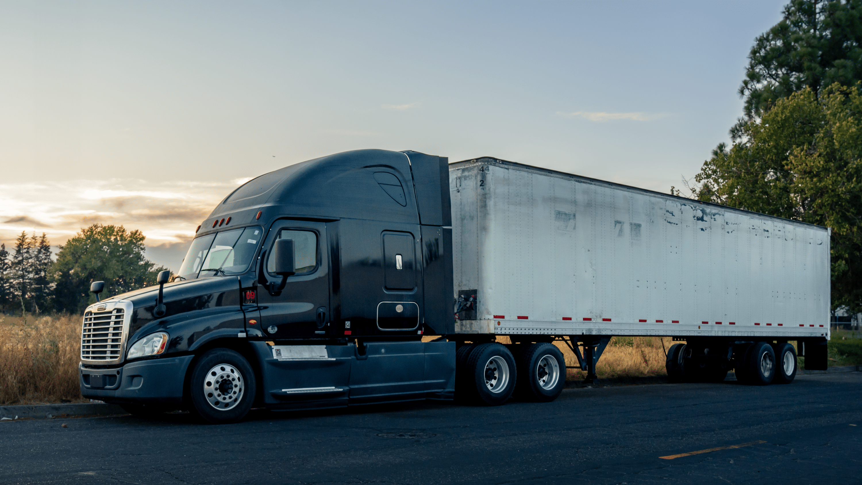 Blue semi truck with a white trailer parked on the road