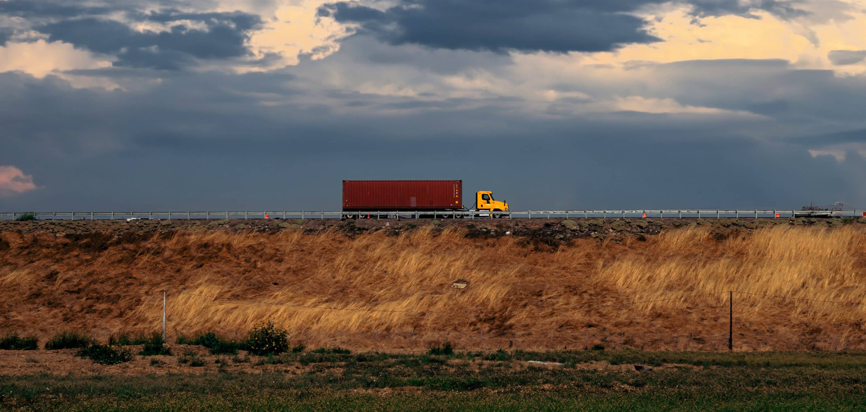 yellow track with a red trailer crossing the bridge