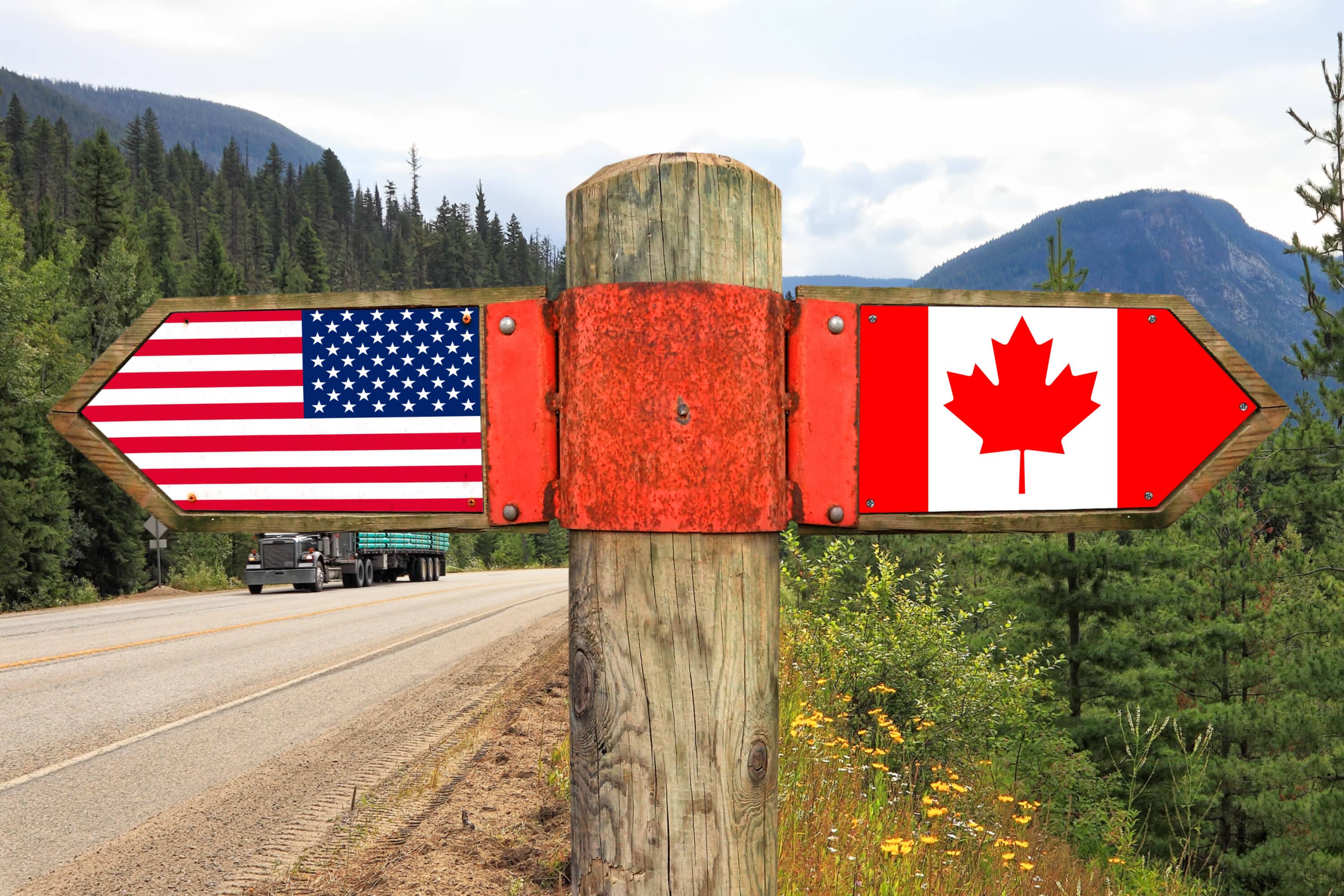 Wooden signpost with 2 arrows - American and Canadian flags
