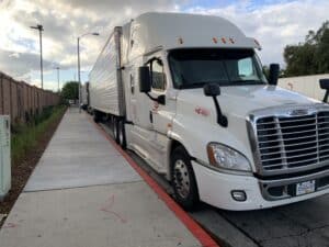 Tractor-trailer stopped along a curb during driver rest periods required by truck driver log book rules.