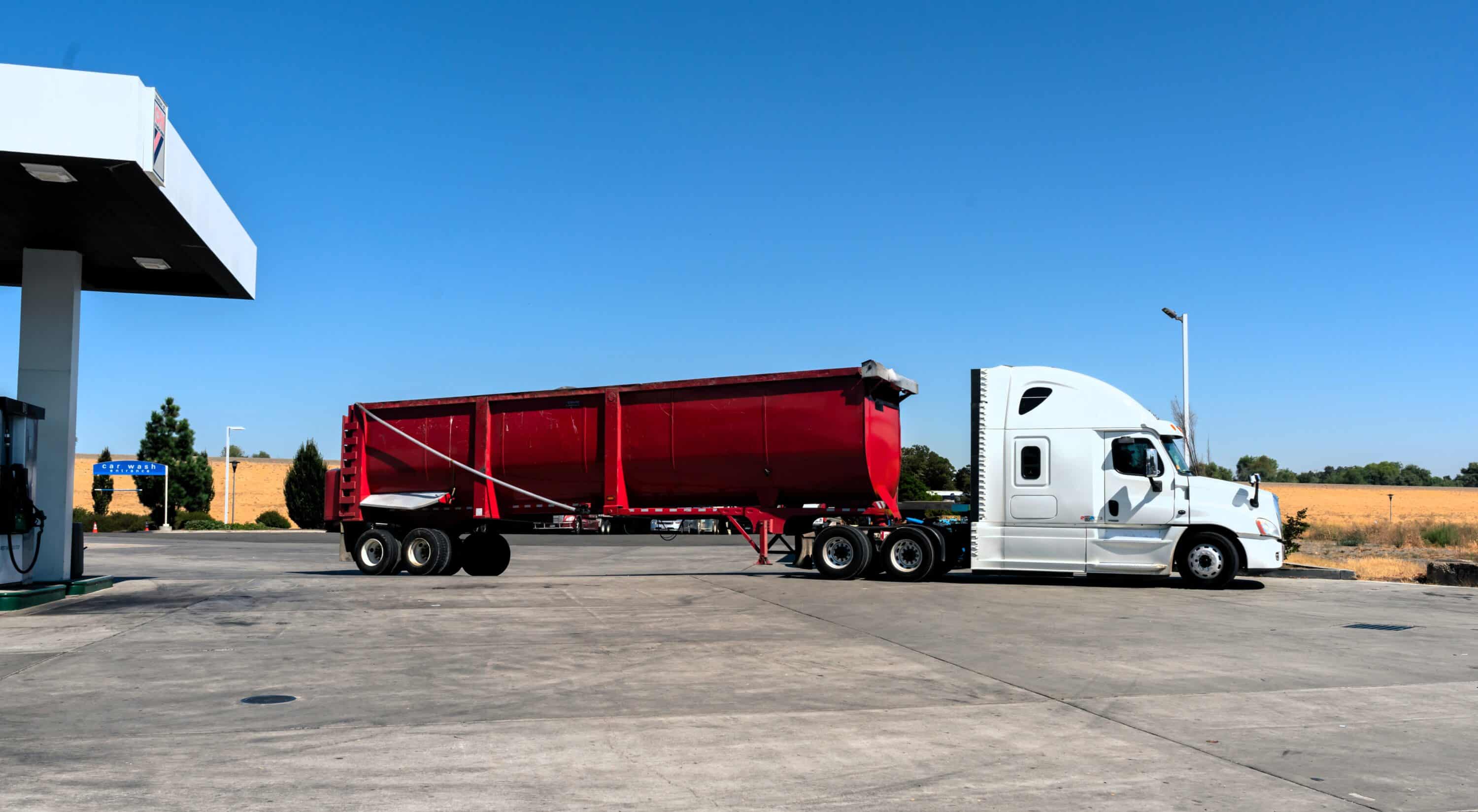 Commercial truck with red dump trailer parked during hours of service compliance stop