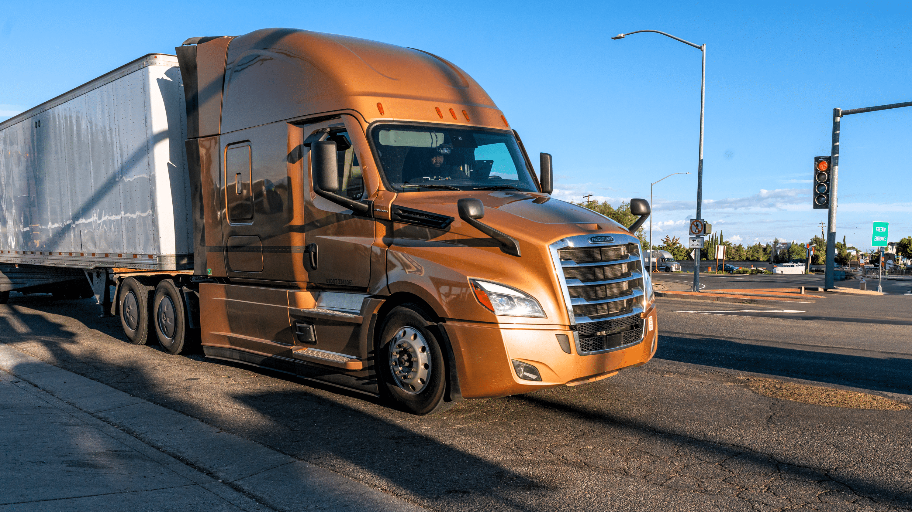 Brown semi-truck with enclosed trailer driving through a city intersection