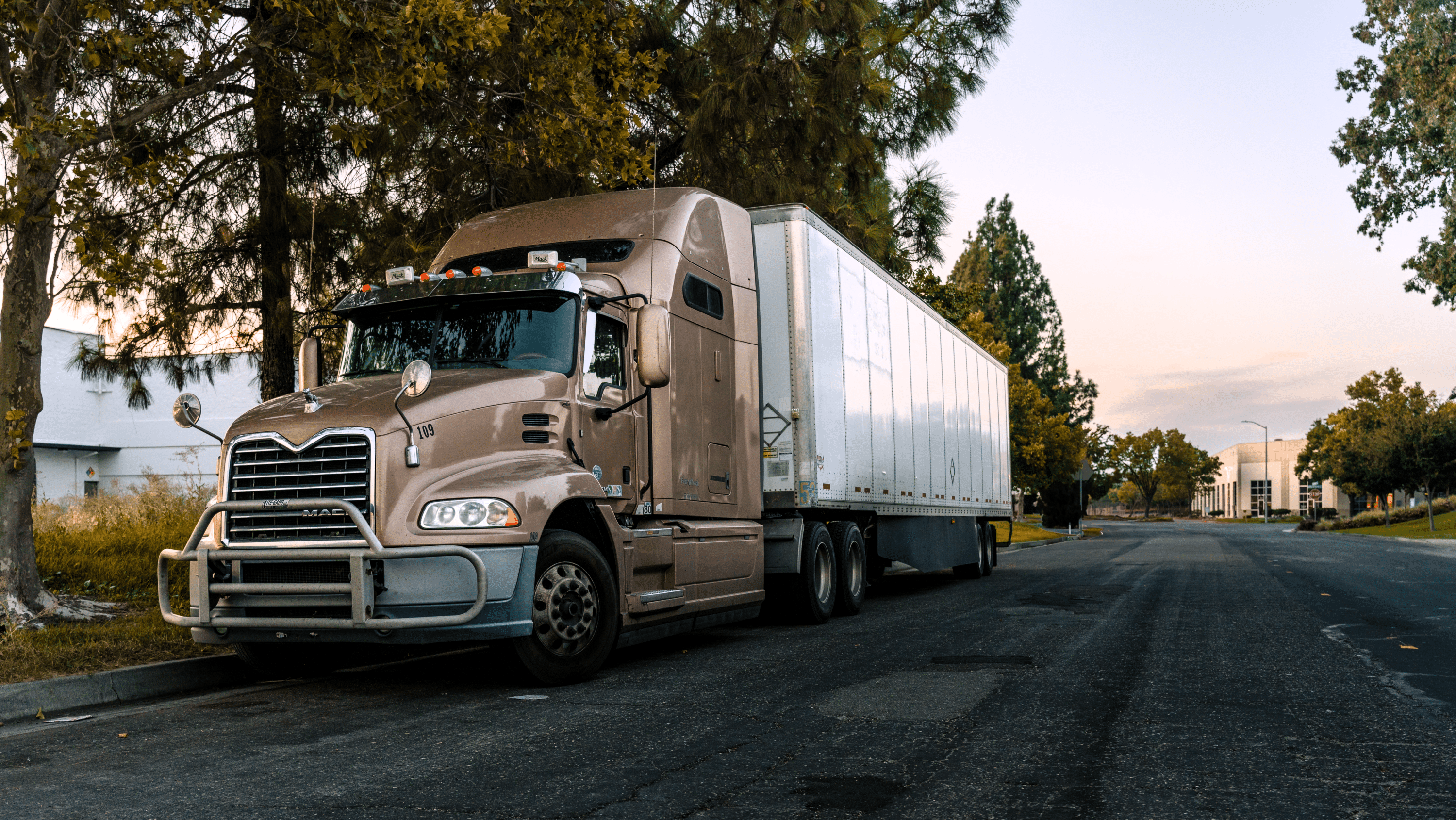 Semi-truck with box trailer parked along a quiet commercial roadway