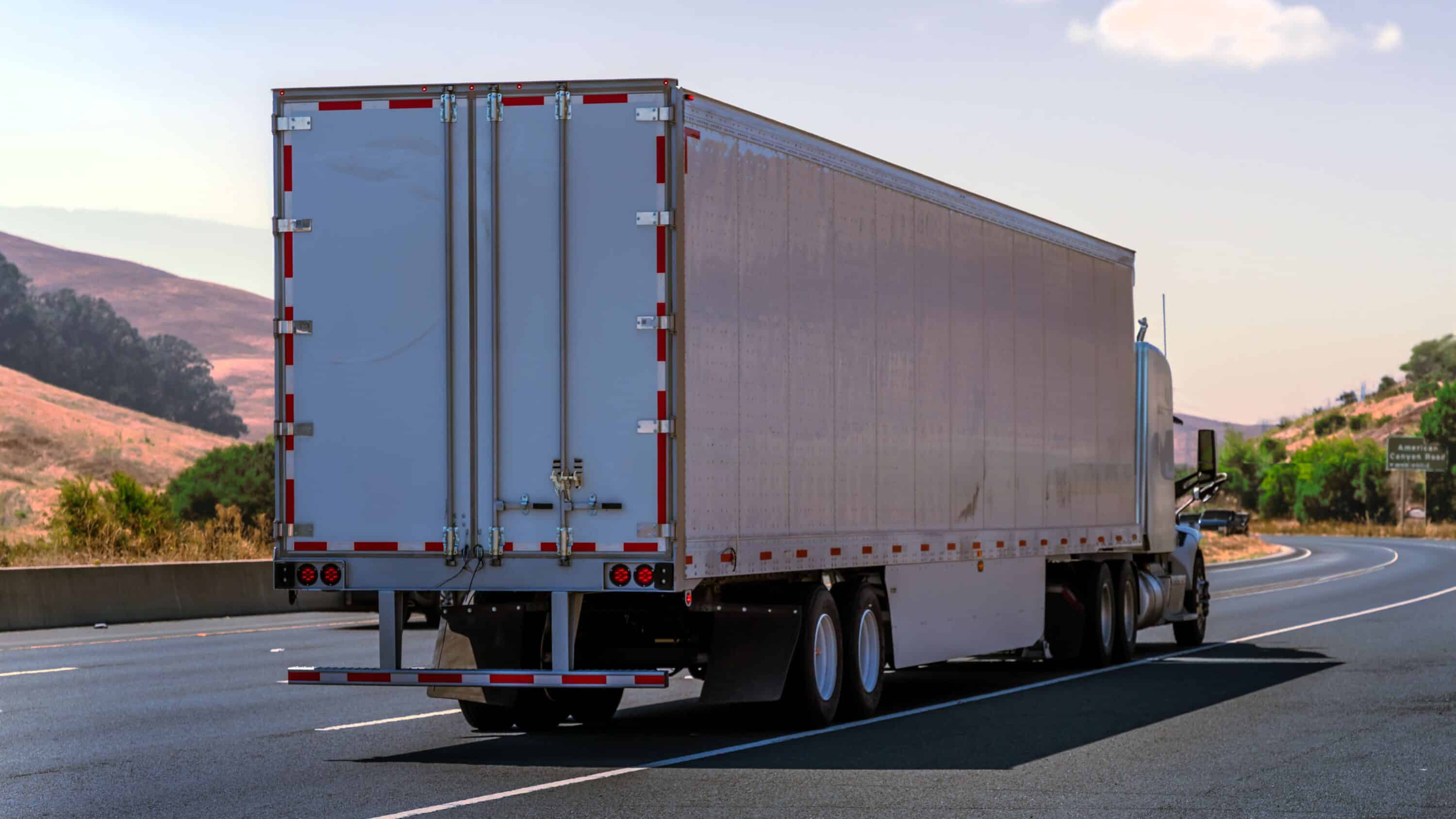 Rear view of a box trailer being hauled by a semi-truck on a highway