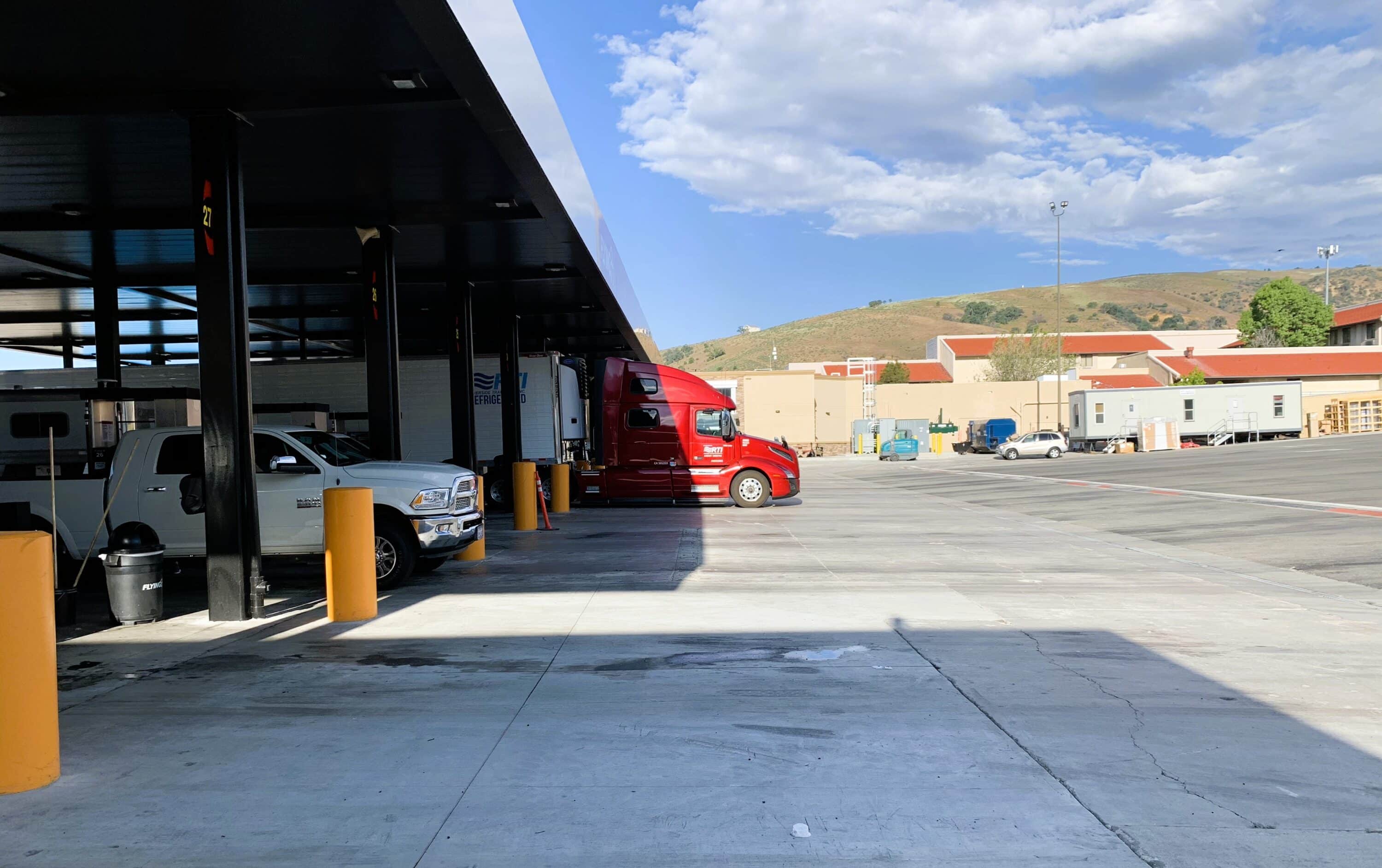 Red semi-truck parked under a covered commercial vehicle parking area