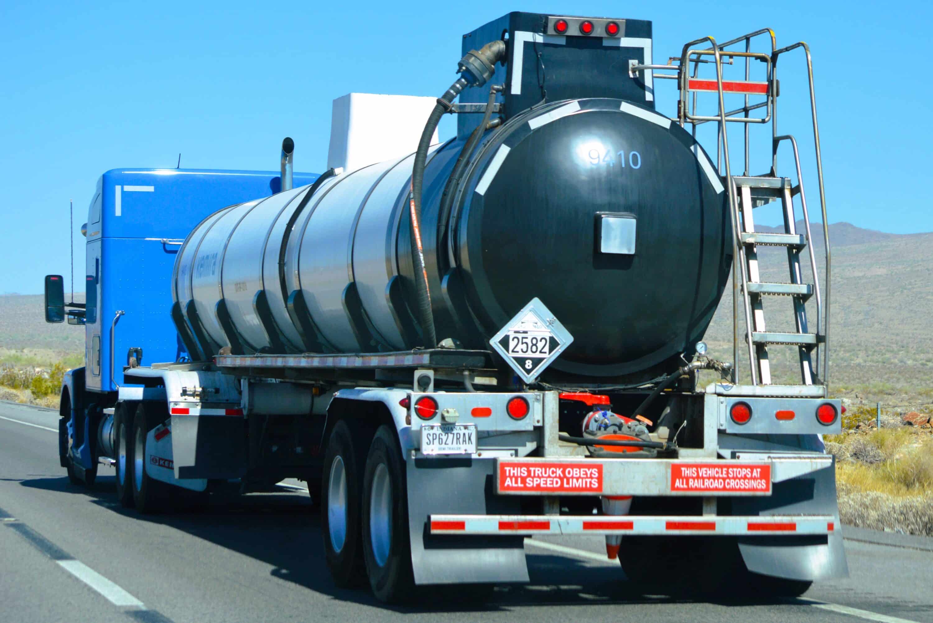 Blue tanker truck transporting liquid cargo on a highway through a desert landscape