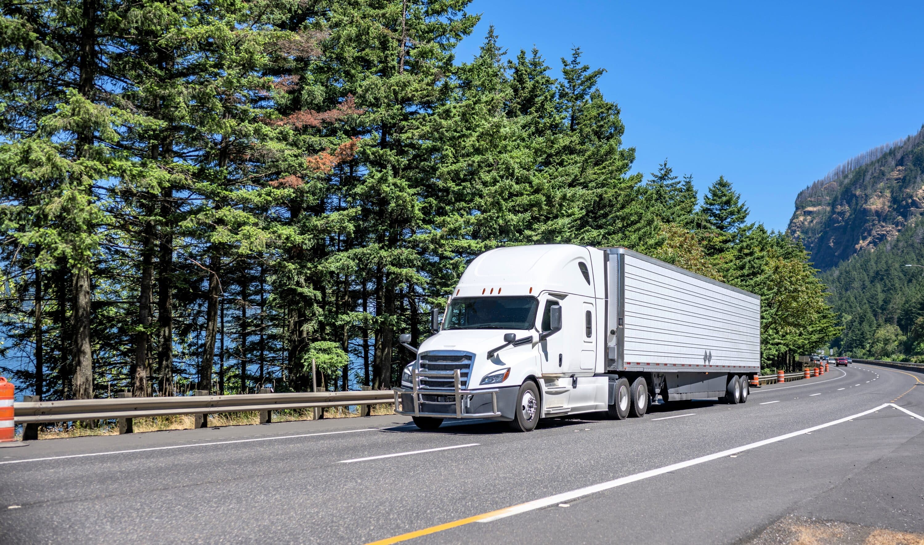 White semi-truck with enclosed trailer driving on a mountain highway