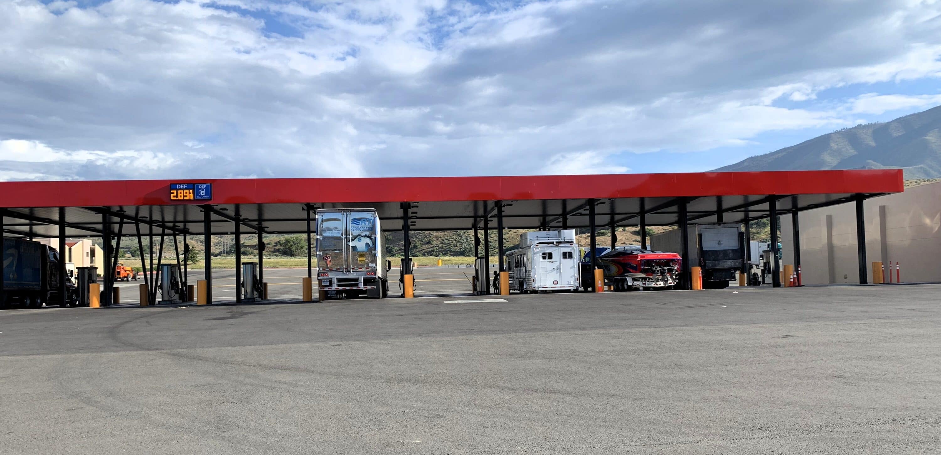 Commercial truck fueling station with multiple trucks parked beneath a covered fuel island