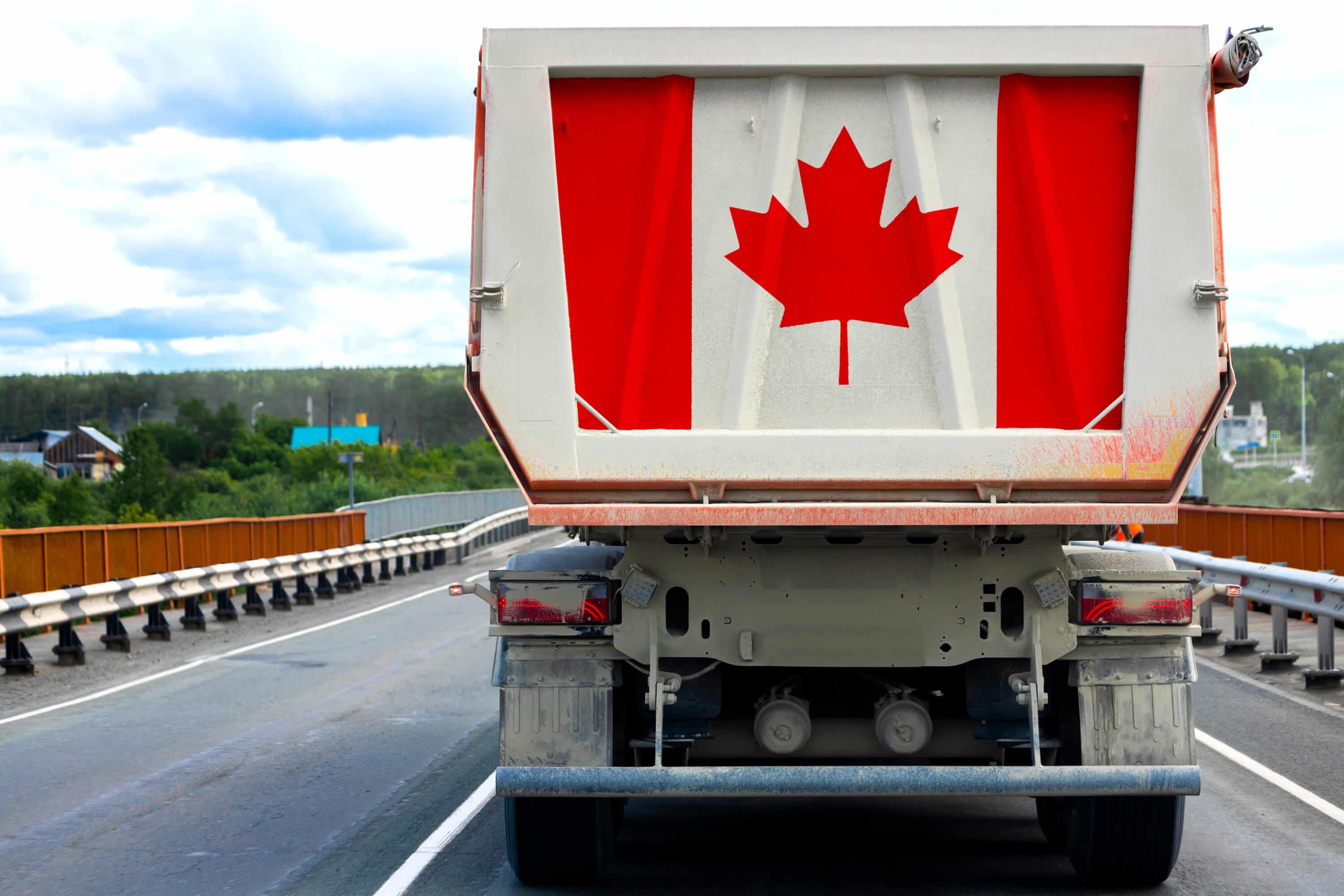 Rear view of a truck displaying a large Canadian flag on a highway bridge