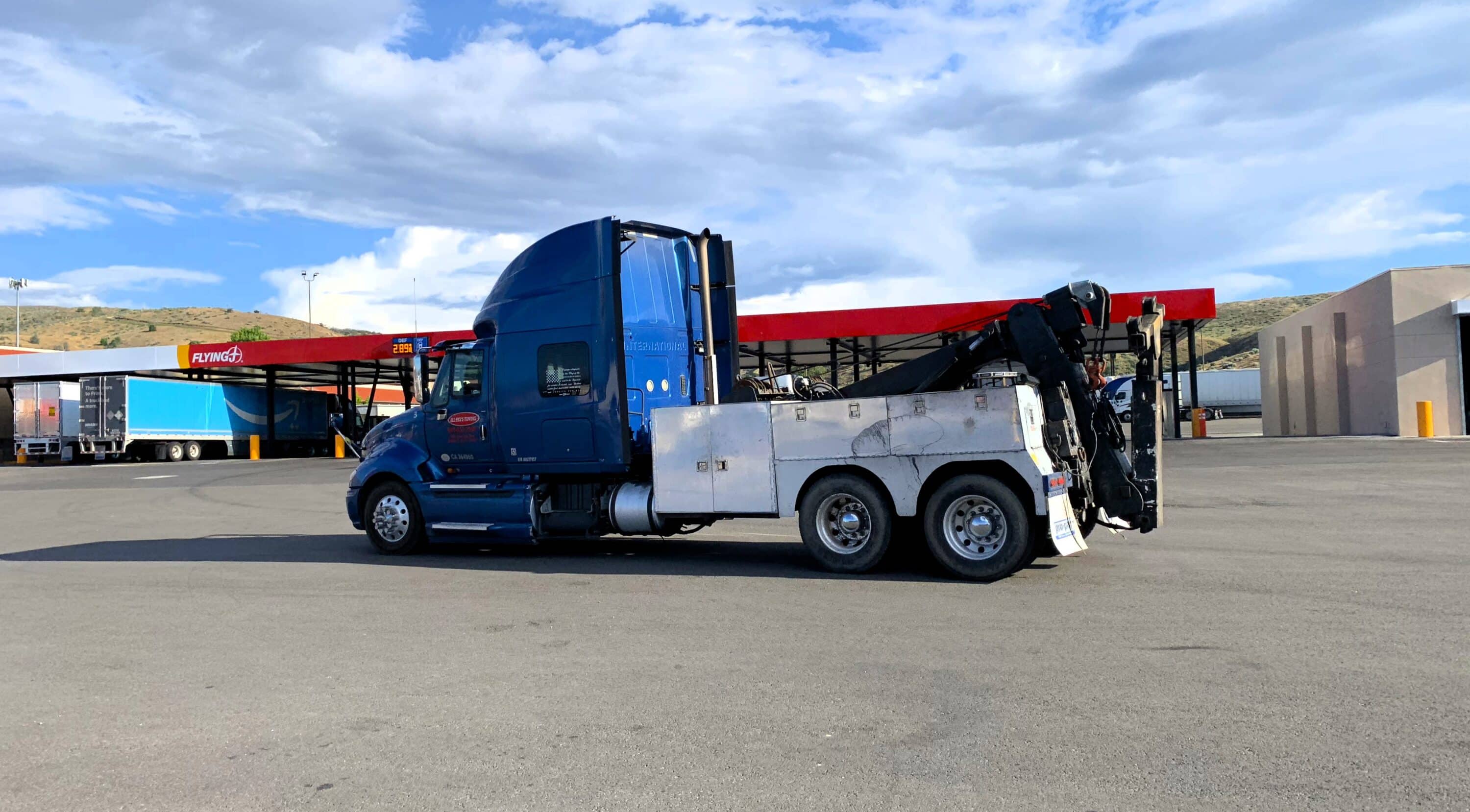 Blue tow truck parked near a commercial truck fueling station